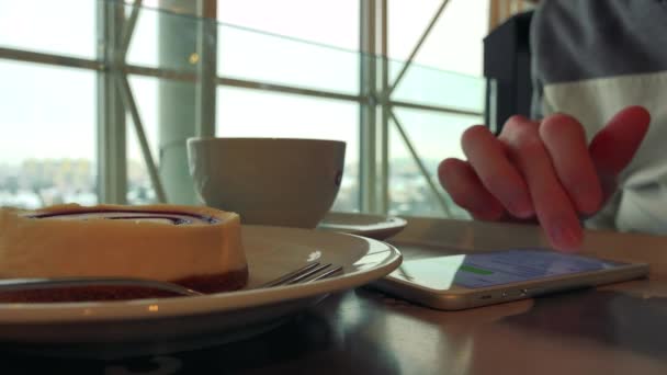 Чоловік зі сніданком в кафе, працює на смартфоні — стокове відео