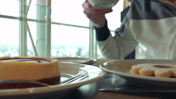 Чоловік насолоджується кавою і десертами в кафе — стокове відео
