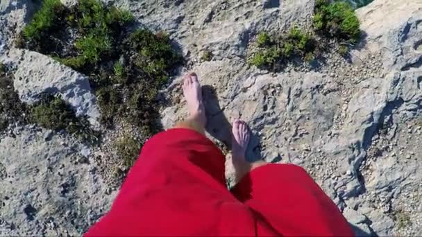 Un uomo cammina fino al bordo di una scogliera in riva al mare — Video Stock