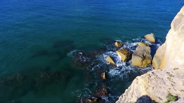 Каменное побережье с камнями в воде и море — стоковое видео