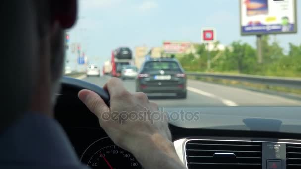 Starší muž jezdí autem - detailní rukou na volantu a silnice s auty v pozadí