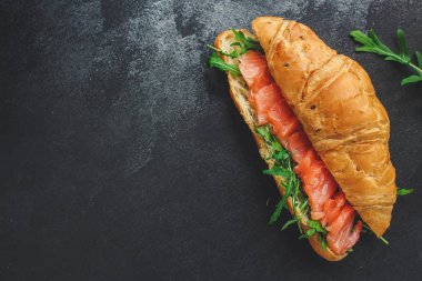 balık sandviçi ve yeşillikler, Smorrebrod (tuzlanmış somon, kruvasan, ekmek, roka ve diğer malzemeler) menü konsepti. Yemek geçmişi. Üst Manzara. Boşluğu kopyala