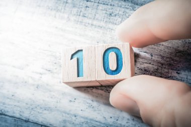 Tahta bloklar tarafından oluşturulan ve masadaki erkek parmaklarıyla düzenlenen 10 numara.