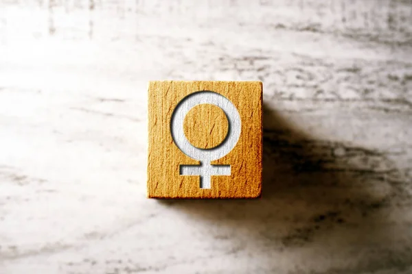 Znak płci żeńskiej na pomarańczowym drewnianym bloku na stole — Zdjęcie stockowe