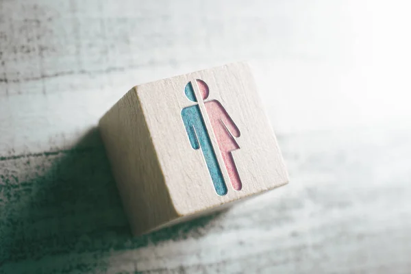 Geslachtstekens voor man en vrouw doormidden gesneden op een houten blok op een tafel — Stockfoto