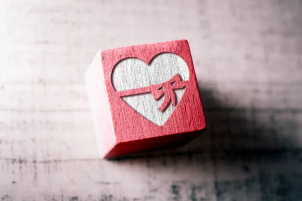 Corazón con una cinta grabada en un bloque de madera rojo en una mesa — Foto de Stock