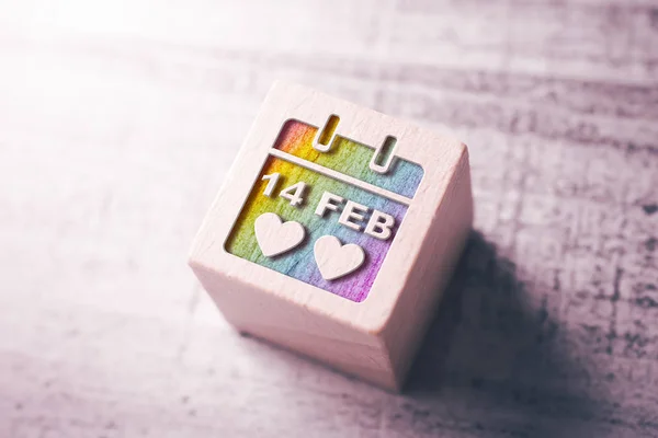 Calendario con fecha 14. Febrero Día de San Valentín en colores de arco iris LGBT grabados en un bloque de madera en una mesa — Foto de Stock