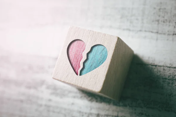 2 pedazos de un corazón roto grabados en un bloque de madera en una mesa — Foto de Stock
