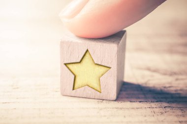 1 Star Ranking On A Wooden Block And Arranged By A Male Finger On A Table