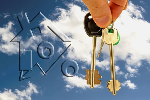 Le chiavi dell'appartamento in mano sullo sfondo del cielo e delle nuvole — Foto Stock