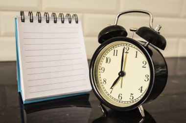 Çalar saat ve defter masada boş sayfa