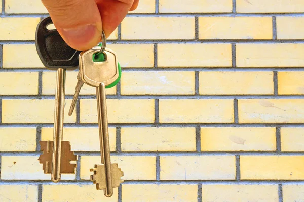 Τα κλειδιά στο διαμέρισμα στο χέρι στο φόντο των σπιτιών — Φωτογραφία Αρχείου