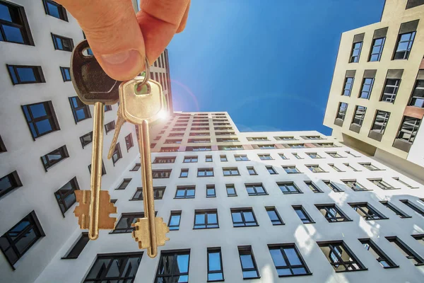 The keys to the apartment in the background of the facade of the house . he concept of sales in the real estate market .