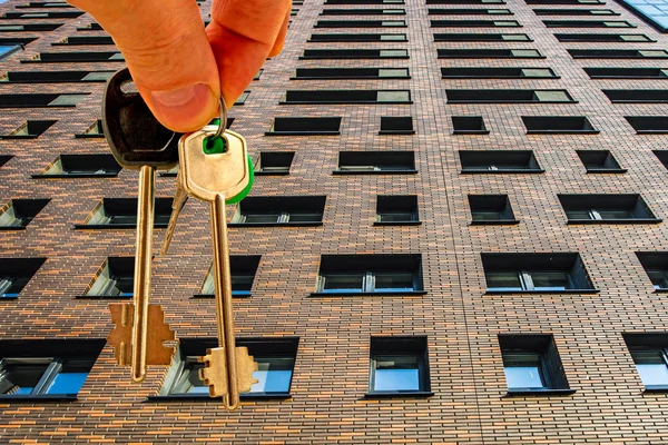 The keys to the apartment in the background of the facade of the house . he concept of sales in the real estate market .