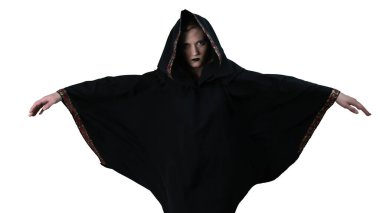 Siyah cüppeli bir kız, sihirli hareketler yapıyor. Beyaz arka planda. Büyücülük..