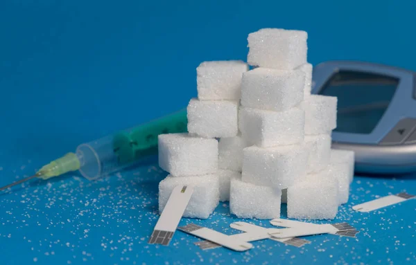 sugar cubes with injection and glucose monitoring on blue background