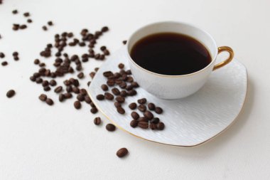 Beyaz fonda bir fincan kahve ve kahve çekirdeği.