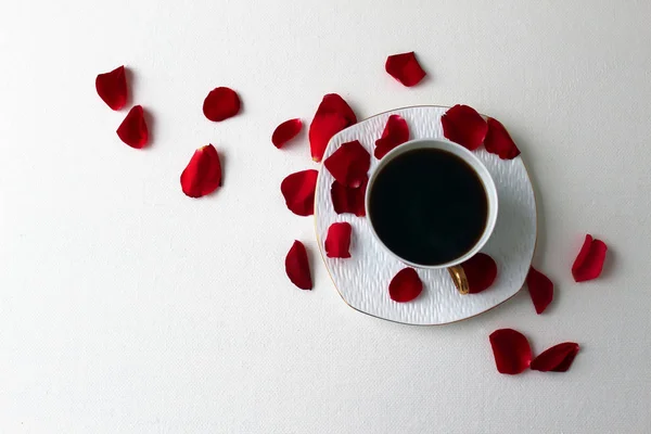 Cup of coffee on a white background and rose petals.               .