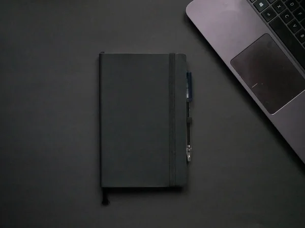Escritório vista superior. Laptop, caneta e notebook sobre fundo preto . — Fotografia de Stock