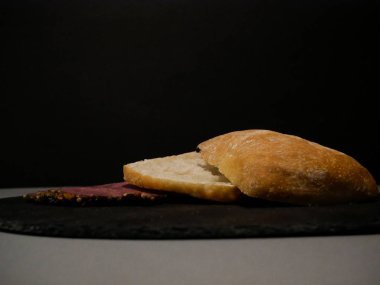 Siyah tabakta dilimlenmiş ekmek ve peynir ve gri arka plan