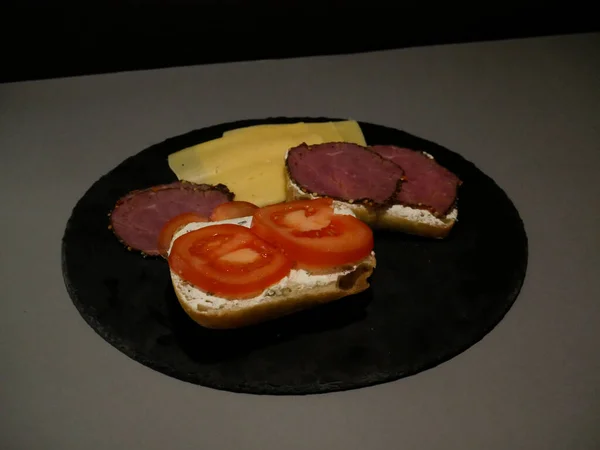 Sliced bread, cheese and ham on black plate and grey background — 스톡 사진