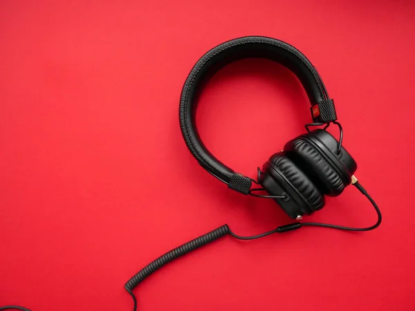 Classic black wired headphones on colored paper background. Retro style. 80s. Pop culture. Top view. — Stock Photo, Image