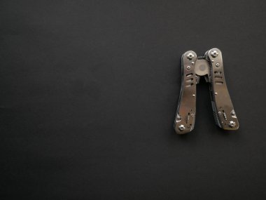 Siyah bir arka planda çelik saplı çoklu alet. Üst görünüm