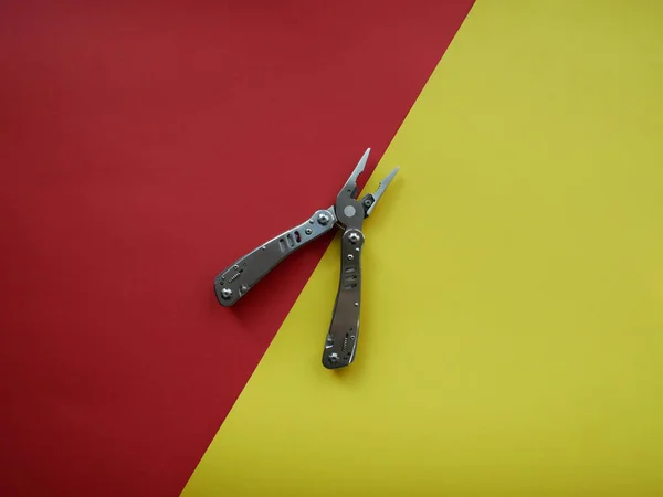 Multi tool with steel handles on a white colored paper background. Top view