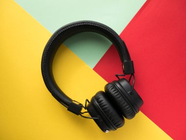 Renkli kağıt arka planda klasik kablosuz kulaklıklar. Retro tarzı. 80 'ler. Popüler kültür. Üst Manzara. Asgari Müzik Konsepti