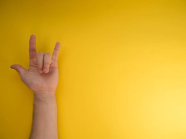 Kadın eli sarı arka planda kaya boynuzları gösteriyor. Metnin için boşluk kopyala.