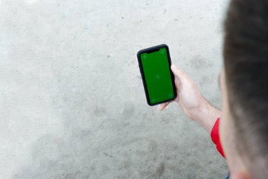 İçeriğiniz için boş yeşil ekranlı akıllı telefonu tutan erkek eli, boş ekranlı cep telefonu kullanan erkek eli