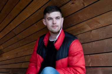 Sağlıklı genç esmer, koruyucu maskeli, ahşap arka planda kulağına asılı.