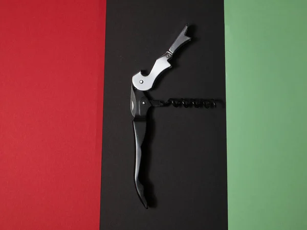 Μαύρο εργαλείο πολλαπλών χρήσεων με ανοιχτήρι μπουκάλι τιρμπουσόν σε χρωματιστό φόντο. — Φωτογραφία Αρχείου