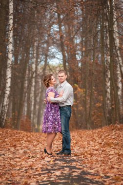 Birbirine aşık çiftler sonbahar parkında yürürler.