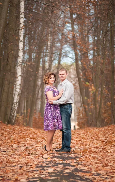 Birbirine aşık çiftler sonbahar parkında yürürler.