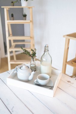 Beyaz masa, bir fincan, çay üstü ve bir vazo çiçek. 