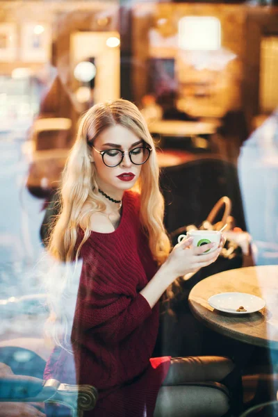 Блондинка в очках, улыбающаяся в бордовом свитере, снег, зима — стоковое фото