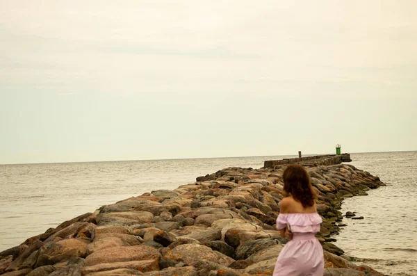 The girl goes on a pier to the lighthouse