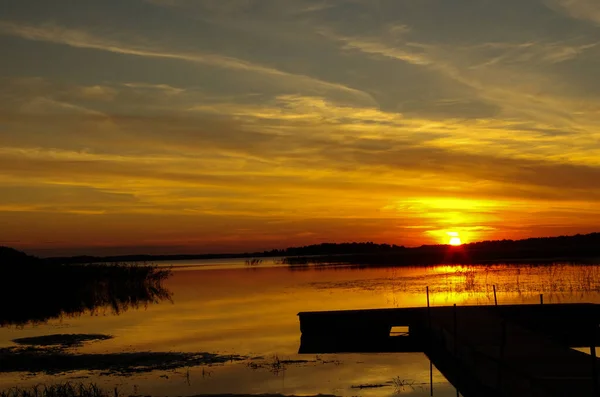 Pasarela al atardecer junto al lago, reflejo del sol —  Fotos de Stock