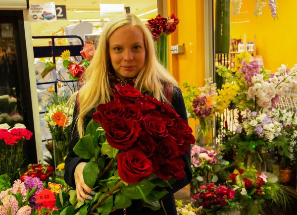 Girl with red roses in a flower shop with prices