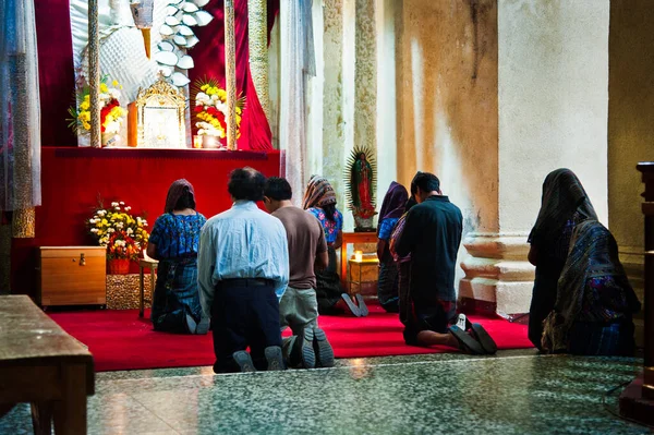 İnsanlar Guatemala 'da dini bir mihrapta diz çöküp dua ediyorlar.