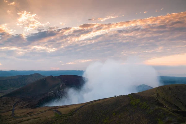 Volcano crater smoking at sunset in Nicaragua, mountain roads seen with people walking