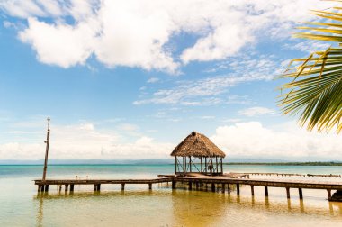 Sakin tropik denizin üzerinde kulübesi olan bir köprü.