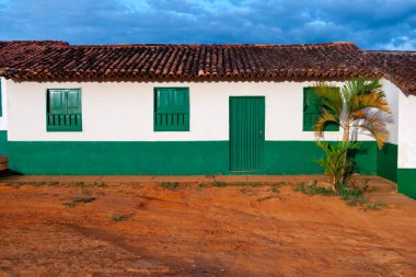 Kolombiya 'dan gelen kırmızı toprağın önündeki yeşil kapılı ve pencereli ev