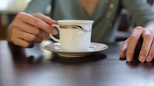 La chica en el café levanta una taza de café y bebidas — Vídeo de stock