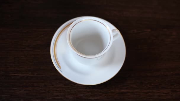 Vista superior del té de la tetera se vierte lentamente en la taza de porcelana — Vídeo de stock