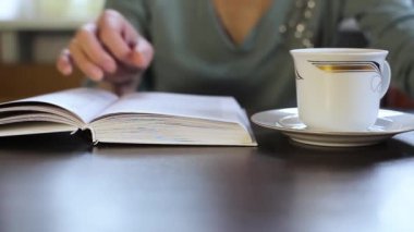 Kız kitap okuyor ve çay içiyor. Yaklaş..
