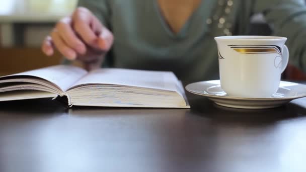 Девушка читает книгу и пьет чай. CLOSE UP . — стоковое видео