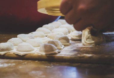 Ev yapımı hamur köfteleri ve koyu arkaplanda et var. El onları özel formdan uzaklaştırıyor. Mutfaktaki tüm aile için hazırlama süreci boyunca hamur işleriyle birlikte hamur işleri yapılıyor. 