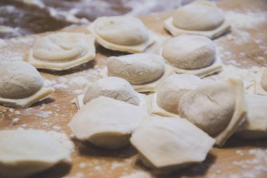 Ev yapımı hamur köftelerini ahşap zemin üzerinde et ve geleneksel hamur işleriyle birlikte yakın plan çek. Ham ürünlerle pişirme, aile ve yiyecek konseptiyle birlikte hepsini yemek için hazırlık olsun.